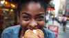 Woman holding a bagel with cream cheese in an urban setting best bagels in nyc halo bagels