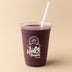 Purple smoothie in a Halo Bagels Cafe cup with a straw on a beige background