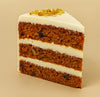 Slice of layered carrot cake with white frosting on a beige background  halo bagels harlem